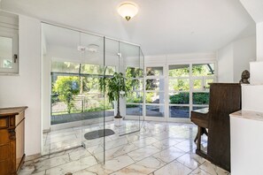A spacious room with a glass door leading to a balcony, a potted plant, and a wooden bench.