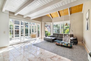 A spacious living room with a large glass door leading to a balcony, a leather sofa, a coffee table, and a hanging light fixture. - Spacious Villa 'Encanto' with 4 Bedrooms, Terrace, Conservatory & Many Activities (Albstadt)