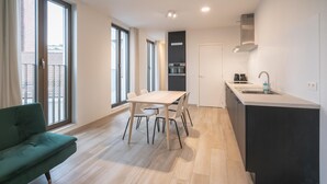 A modern apartment with a dining area, kitchenette, and a green sofa. - City Rhythm Abode for 10 in Antwerp (Antwerp)