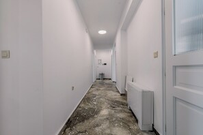 Ein Korridor mit weißen Wänden, einem Marmorboden und einem Heizkörper rechts.