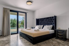 A bedroom with a large bed, a nightstand, and a view of a pool through a sliding door. - BRAND NEW LUXURY 4-BEDROOM VILLA IN CENTRAL LOCATION -70 METERS FROM THE SEA! (Nydri)
