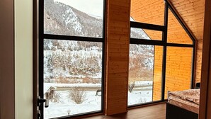 Una habitación con suelo de madera, ventanas amplias y techo inclinado.