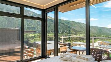 Hotelkamer met grote ramen en uitzicht op een bergachtig landschap.