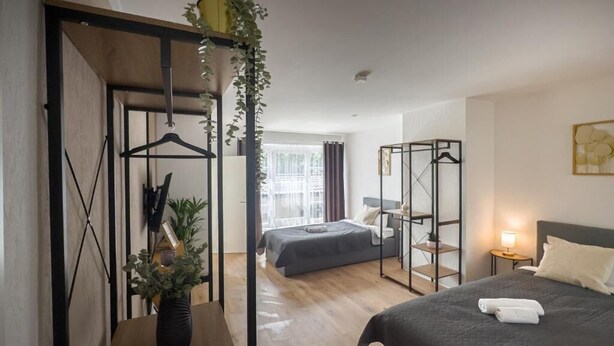 A hotel room with a bed, a bedside table, a hanging plant, a wardrobe, and a window with curtains. - Grambker Heerstraße (Bremen)
