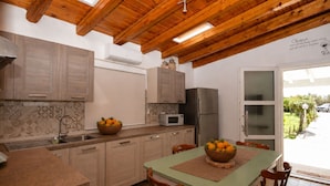 Une cuisine avec des meubles de rangement en bois, un four à micro-ondes, un réfrigérateur et une table à manger avec des chaises.