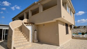 A modern building with a stone staircase leading to a door, a flat roof, and a stone wall. - Stunning  villa for 4 guests with A/C, WIFI, private pool, TV, patio and panoramic view (Marina Di Ragusa)