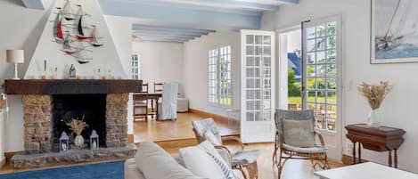 A spacious living room with a stone fireplace, a large window, and a view of the outdoors.
