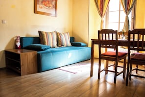 A living room with a sofa, a wooden table, and a chair. - Apartments Belopeški Dvori (Kranjska Gora)