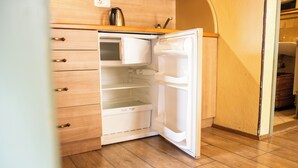 Une cuisine avec des meubles de rangement en bois, un réfrigérateur blanc et un plan de travail en bois.