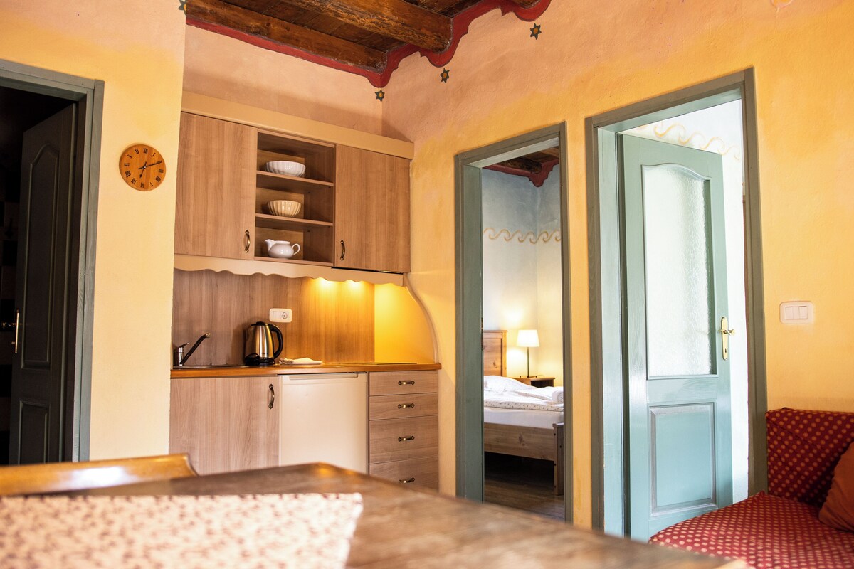 Une pièce comprenant un lit, une armoire en bois, une horloge et une porte donnant sur une autre pièce.