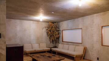 A room with a wooden coffee table, two sofas, a whiteboard, and a decorative plant.