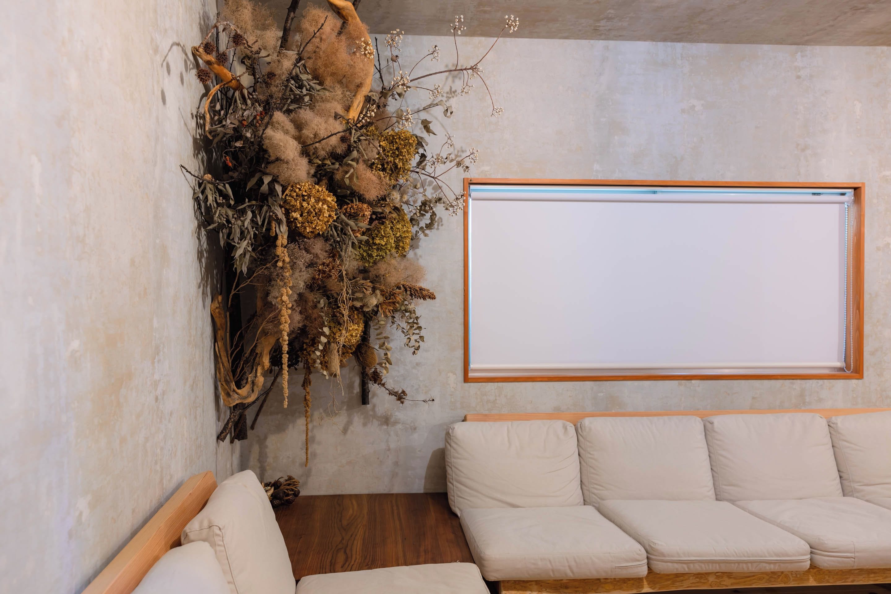 A room with a white sofa, a wooden floor, and a wall-mounted projector screen.