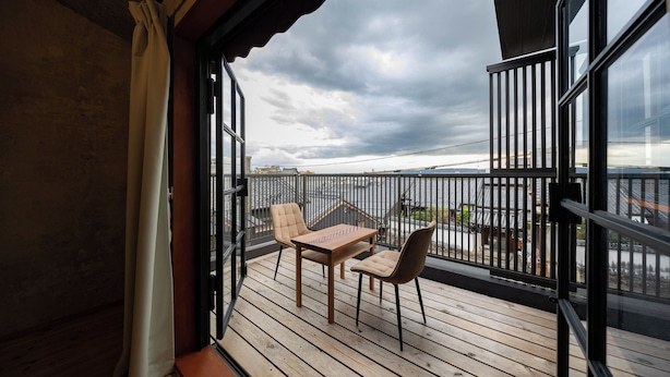 En balkon med et træbord og to stole, der udover en by med traditionelle bygninger.