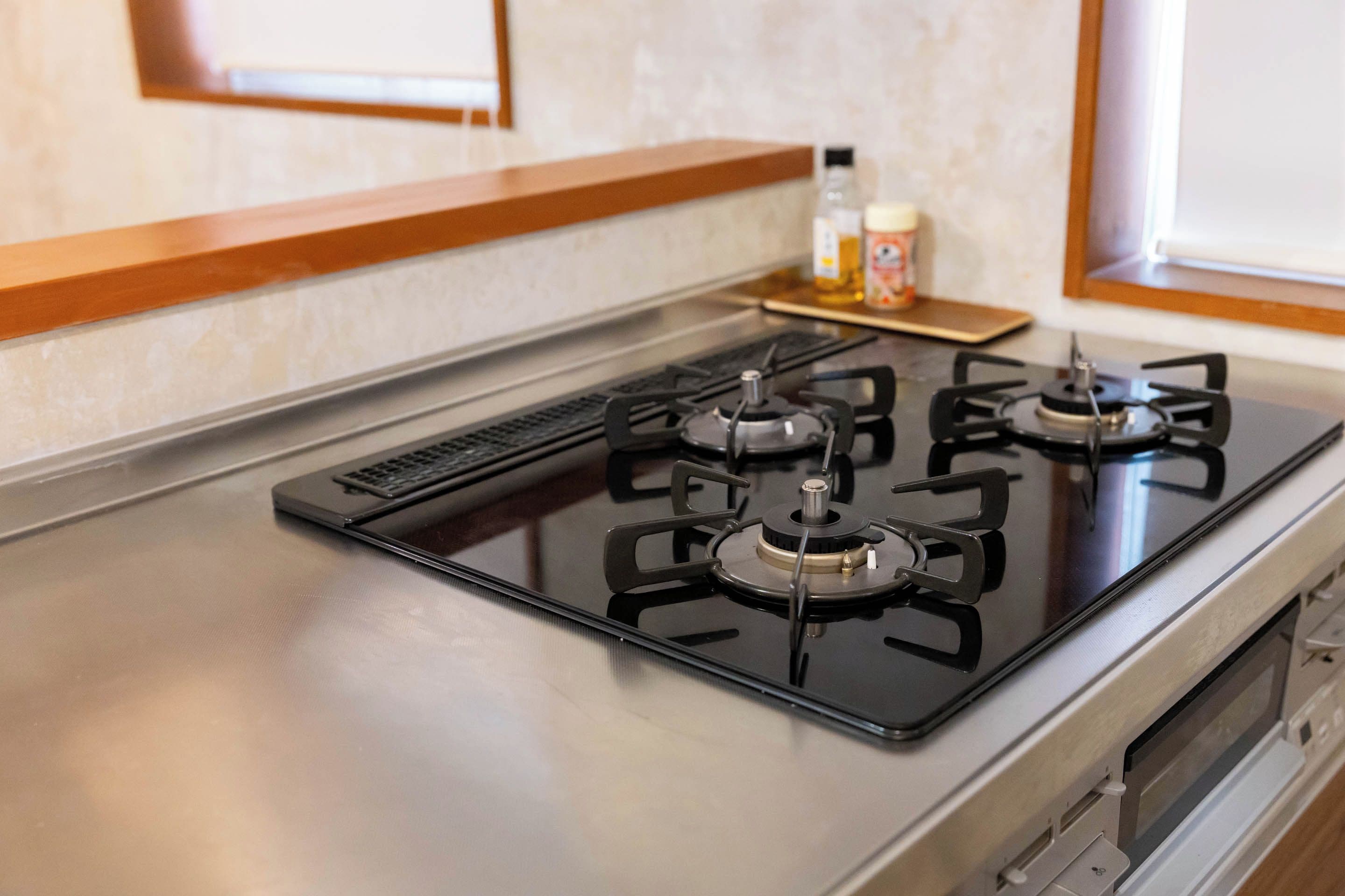Una cocina con estufa a gas, extractor de humos y ventana con vistas.