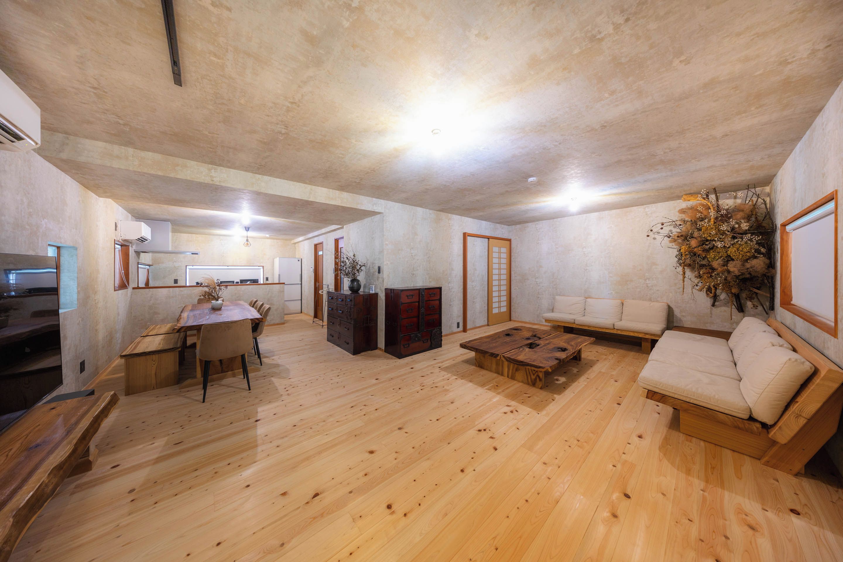 Uma sala de estar ampla com piso de madeira, um sofá, uma mesa de centro e uma mesa de jantar com cadeiras.
