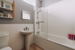 Un bagno con doccia vetro, lavabo su piedistallo e toilette.