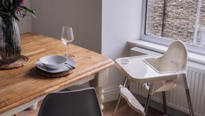 Un'area pranzo con un tavolo in legno, un'alzatina bianca e un vaso con fiori.