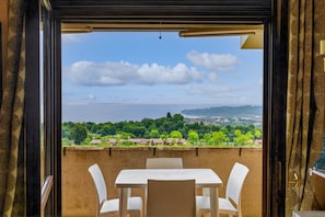Ein Balkon mit Tisch und Stühlen, der einen schönen Ausblick auf eine Landschaft mit Bäumen und fernen Hügeln bietet.