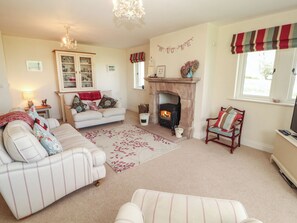 A cozy living room with a fireplace, a sofa, a chair, and a dining table. - Thimble Hill (Carlisle)