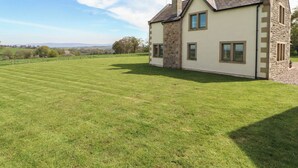A two-story house with a stone facade, a large lawn, and a clear sky. - Thimble Hill (Carlisle)