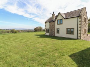 A two-story house with a stone facade, a large lawn, and a clear sky. - Thimble Hill (Carlisle)
