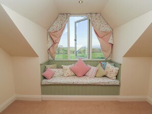 A room with a bay window, a built-in bench with cushions, and a view of the outdoors. - Thimble Hill (Carlisle)