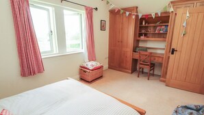 A bedroom with a bed, a desk, a chair, a wardrobe, and a window with curtains. - Thimble Hill (Carlisle)