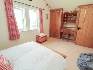 A bedroom with a bed, a desk, a chair, a wardrobe, and a window with curtains. - Thimble Hill (Carlisle)