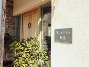 A house with a wooden door, a potted plant, and a sign that reads 'Thimble Hill.' - Thimble Hill (Carlisle)