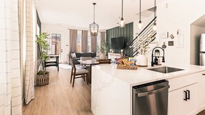 A modern kitchen with a large island, stainless steel appliances, and a dining area with a sofa and table.