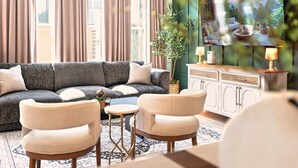 A living room with a sofa, two armchairs, a small table, and a cabinet.