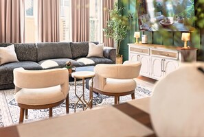 Ein Wohnzimmer mit einer Couch, zwei Sesseln, einem kleinen Tisch und einem Schrank.