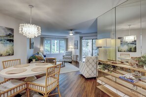 A spacious living area with a dining table, chairs, and a large mirror. - Sunset Rentals | Colonnade Club 147 (Hilton Head Island)