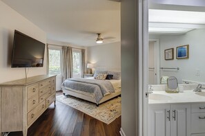 A bedroom with a bed, dresser, TV, and a bathroom with a sink and mirror. - Sunset Rentals | Colonnade Club 147 (Hilton Head Island)