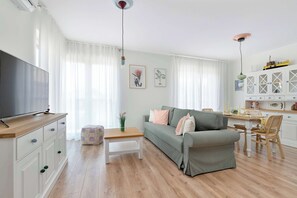 A living room with a sofa, coffee table, TV, and a dining area with a table and chairs. - Air-conditioned Apartment | Parking & Balcony (Łeba)