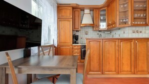 Una cocina con armarios de madera, una mesa de comedor y un reloj en la pared.