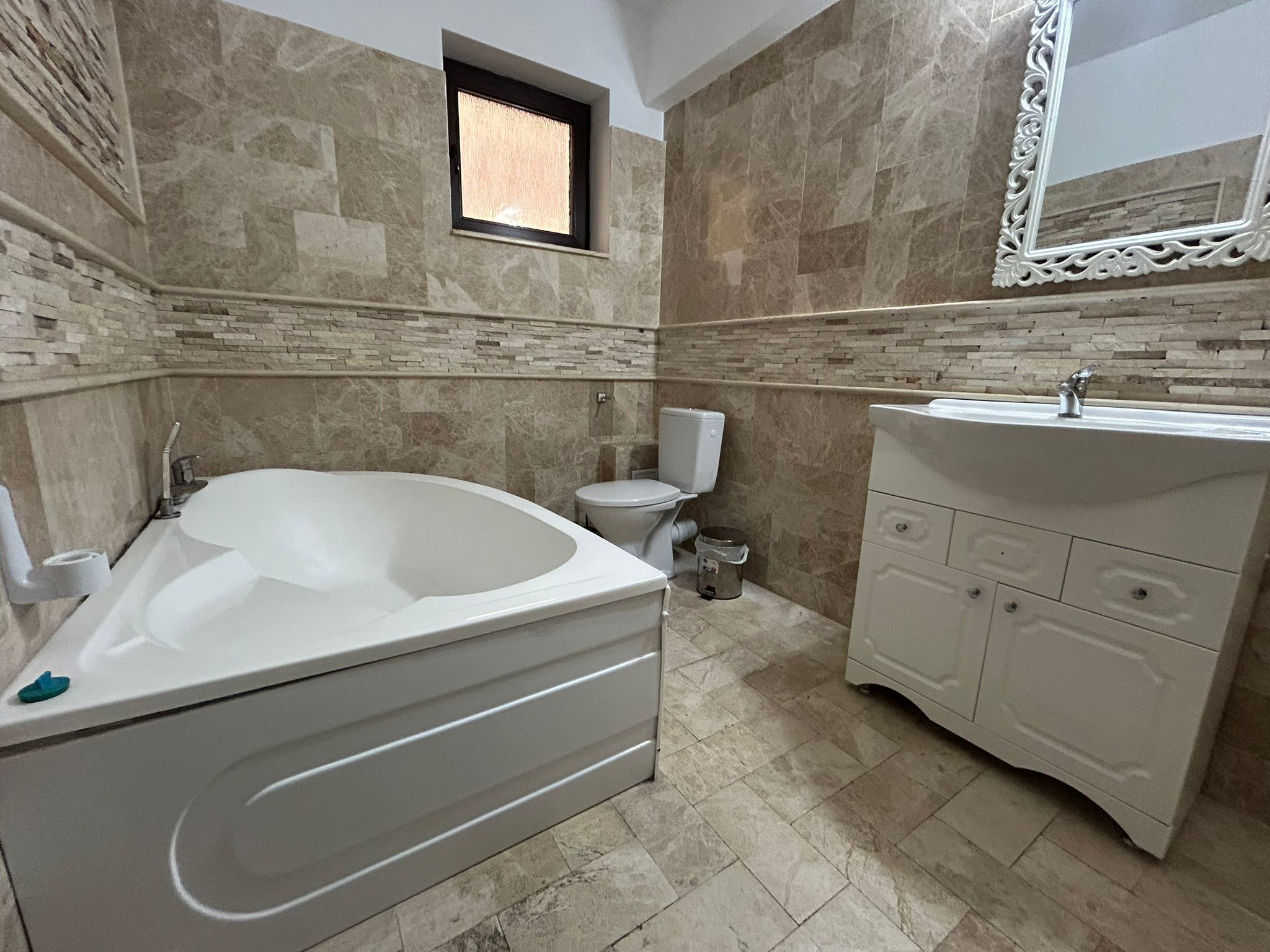 Un baño con bañera independiente, inodoro, lavamanos y ventana.