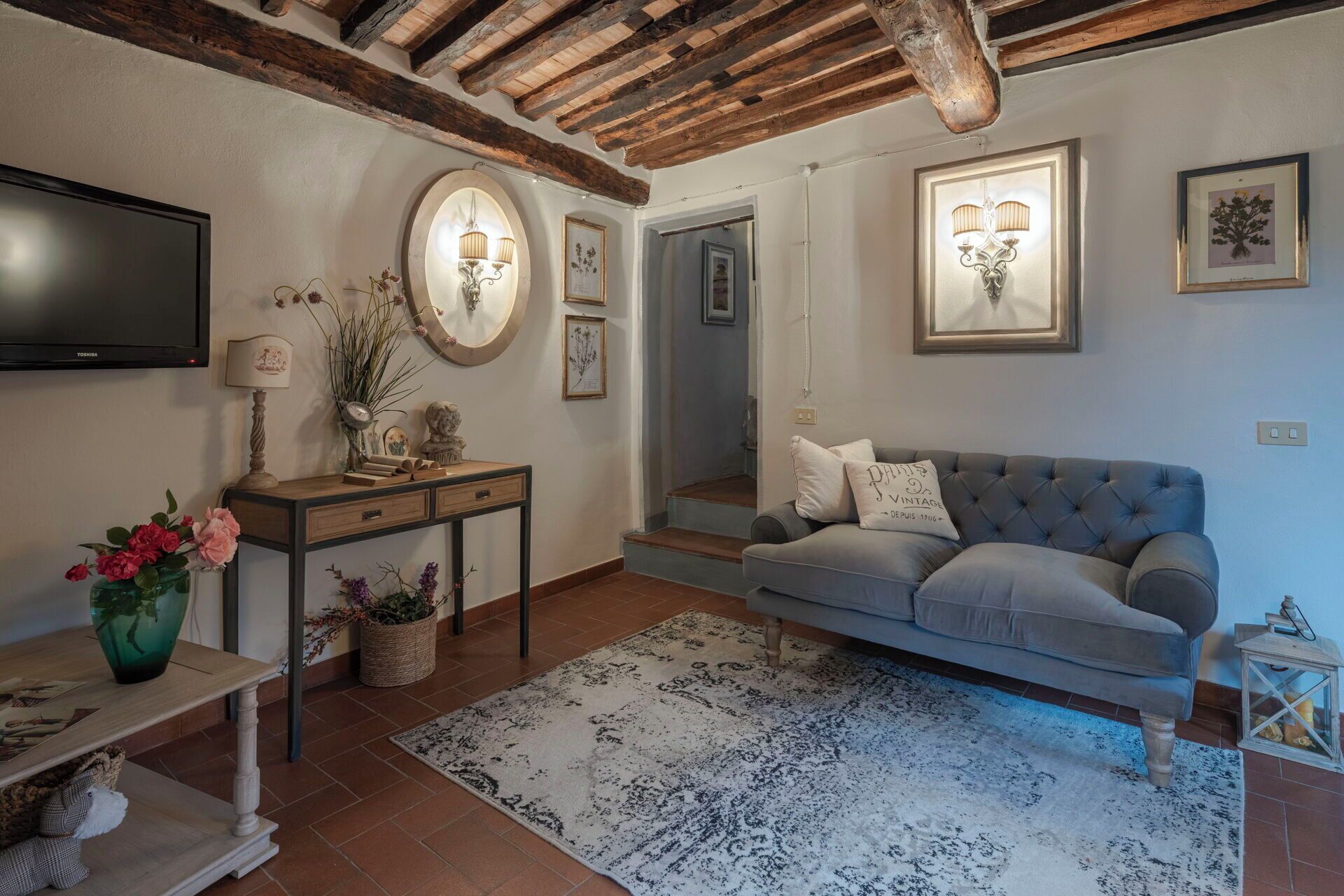 Un salon comprenant un canapé, un téléviseur, une console ornée d’objets décoratifs et une cheminée.