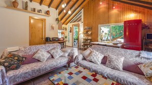 A cozy living room with a wooden ceiling, two patterned sofas, a tiled coffee table, and a red appliance. - Rural Cabin 'La Casita de la Font del Bosc'. SPA. Charming Entire Rural House (La Font del Bosc)
