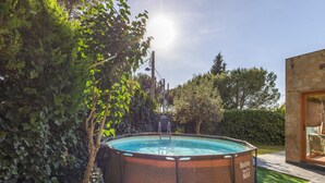An outdoor swimming pool surrounded by lush greenery, a stone wall, and a clear sky. - Rural Cabin 'La Casita de la Font del Bosc'. SPA. Charming Entire Rural House (La Font del Bosc)
