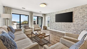 A modern living room with a large TV, comfortable seating, and a view of the beach. - beachfront townhome located directly on the sand in a private gated community (Panama City Beach)