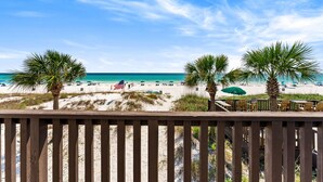 A beach view with palm trees, a wooden deck, and a sandy beach. - beachfront townhome located directly on the sand in a private gated community (Panama City Beach)
