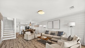 A spacious living area with a wooden floor, a sofa set, a coffee table, and a staircase leading to another room. - beachfront townhome located directly on the sand in a private gated community (Panama City Beach)