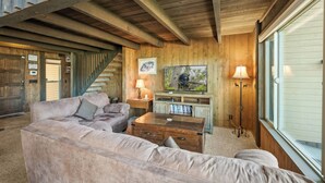 Un interior de madera con un sofá, una mesa de centro, un televisor y una escalera.