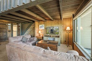 Ein Holzinnenraum mit einer Couch, einem Couchtisch, einem Fernseher und einer Treppe.