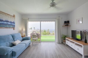 Un salon avec un canapé, une télévision et un balcon offrant une vue agréable.