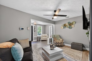 A modern living room with a ceiling fan, a flat-screen TV, and a coffee table. - 2br Getaway Near I-75 World Cup 1 Bedroom Home (Jonesboro)