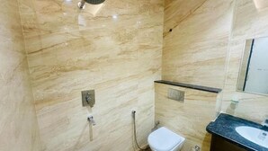A modern bathroom with a marble wall, a toilet, a bidet, a sink, and a showerhead. - DD Green Residency (New Delhi)