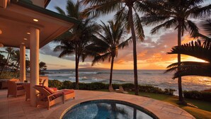 A pool area with lounge chairs, palm trees, and a view of the ocean at sunset. - Beachfront / Oceanfront Private Home  Sleeps 8 (Wailea)