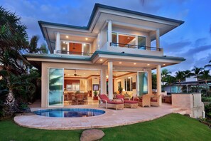 A two-story house with a swimming pool, outdoor seating, and a covered patio.